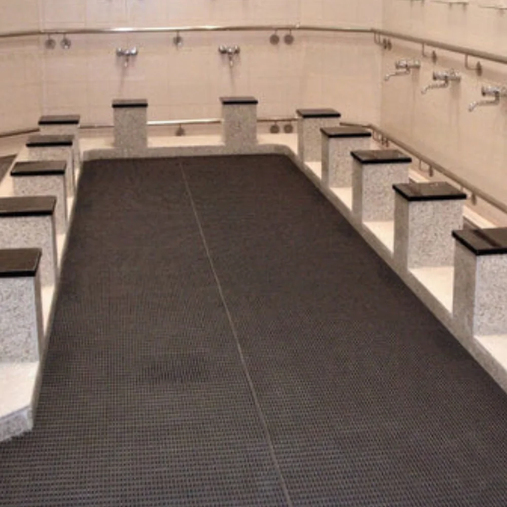 Durable black Ablution Mats installed on the floor of a wudu area with marble seating.