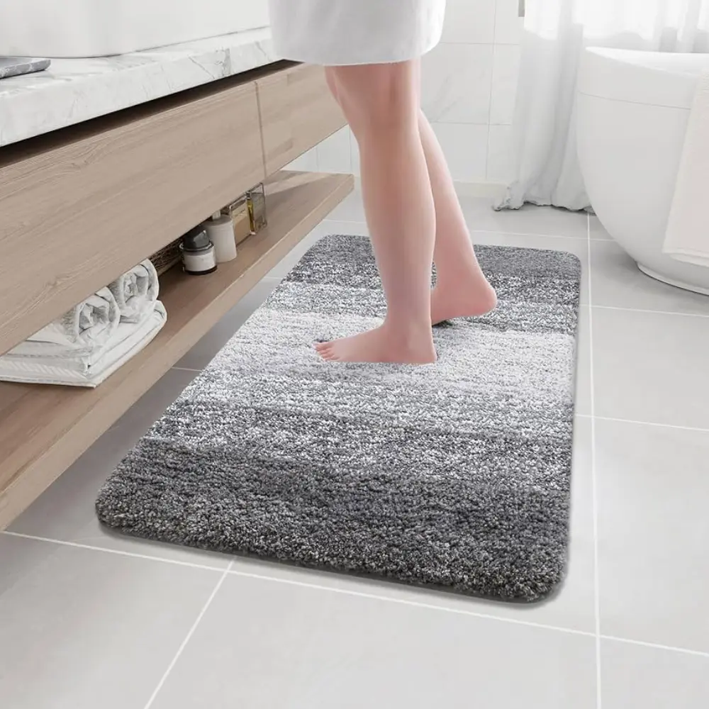 Gray textured Bathroom Mats positioned in front of a modern glass shower door to absorb water.
