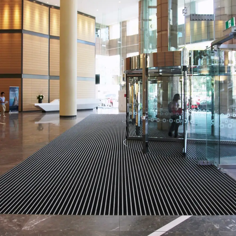 Modern lobby with glass revolving doors and large Entrance Mats in Commercial Buildings for safety.
