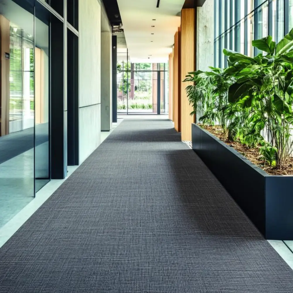 Sleek, grey Rubber flooring Dubai in a modern commercial office hallway with greenery.